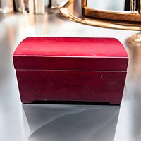 Wooden lacquer finish music box photographed on tabletop with natural light showing top and front side, highlighting surface scuffs.