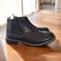 Side view of a pair of brown leather Chelsea boots showing elastic panels and pull tabs