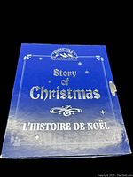 Closed blue book-shaped carrying case with 'Story of Christmas' title and festive star decoration, showing the front cover of the nativity set box.