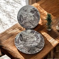 Top view photo showing 2 stacked plates and one bowl placed on a wooden surface with sunlight.