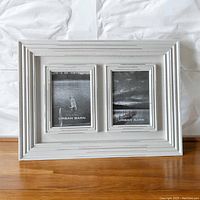 White distressed wood frame with two 5x7 openings showing placeholder photos from Urban Barn, placed on a wooden floor against a white background.