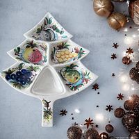 Top view of white ceramic serving platter shaped like a Christmas tree with six sections, each handpainted with colorful fruit and floral designs.