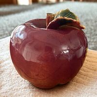 Large vintage Italian hand-painted ceramic apple showing red glossy surface, green and brown leaf, and brown stem.