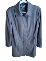 Front view of dark midi length women's jacket with collar and button-up front concealed by fabric flap.