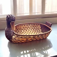 Duck shaped basket with woven dark and light fibers, photographed near a window for natural lighting.