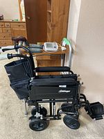 Side view of collapsed Airgo wheelchair beside walker and blood pressure monitor on table