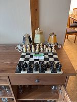 Three alabaster lamps and chess board with pieces on wooden surface, overview of all items