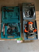 Lot showing Makita drill kit in teal case with accessories and Black & Decker router kit in blue case with router and wrenches