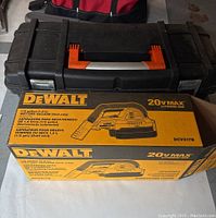 Black plastic toolbox with red handle and metal latches alongside its original yellow DeWalt box for the Wet/Dry Vacuum DCV517B