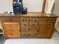 Full front view of pine wood sideboard showing two cabinet doors and seven drawers with metal handles.