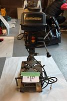 Front view of Mastercraft drill press showing the brand on the motor cover and power switch with cord around the base.