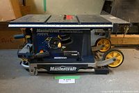 Side view of table saw on floor showing Mastercraft foldable frame and wheels collapsed
