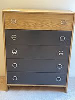 Front view of the 5 drawer dresser with top drawer wood finish and lower drawers in dark gray, featuring chrome circular handles.