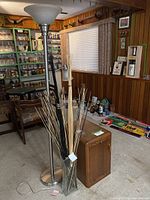 Wide view showing all three items: floor lamp, glass vase with sticks, and wood side table
