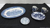 Full set shown on black background: Wedgwood platter, Sadek plate and mugs, Staffordshire bowl