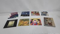All 8 books arranged on flat surface, front covers visible showing diverse art images and titles