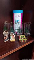 Lolita wine glass with original box, four Spode Christmas Tree glasses, Nativity figurines of Mary and Joseph, and small Christmas box on wooden shelf