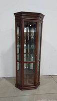 Front view of the solid wood corner curio cabinet showing full height, glass panels, and shelves