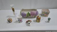 Full assortment of vintage flower-themed items: frosted glass vase, Sadek planter, wooden flower box, porcelain basket, floral mugs, nightlight, and miniature hand vase