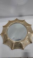Front view of the round Soleil mirror with gold tone sunburst scalloped frame showing the mirror surface and frame detail.