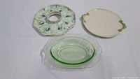 Three green-themed server pieces: central ceramic dip dish with hole, ceramic platter with handles, and green uranium glass bowl