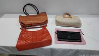 All four handbags displayed on white table: brown vegan ostrich leather tote, beige wicker-handle handbag, brown Cole Haan tote, black Kenneth Cole clutch.
