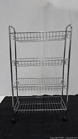 Front view of metal wire shelf stand with four wire basket shelves and wheels.