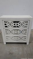 Front view of the white mirrored chest cabinet showing three drawers with decorative mirrored panels and white knobs.
