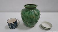 Green ceramic Four Corner dragonfly vase, Urban Bungalow mug, and Burgess & Leigh ivy bowl shown from front.