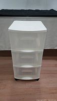 Front view of the white 3-tier plastic storage container showing drawers and wheels