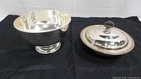 Silver plated soup tureen components shown separately on black cloth, including bottom vessel and lid.