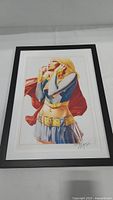 Framed, signed print of Supergirl comic cover showing full artwork and frame.
