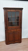 Full view of the vintage corner cabinet showing the overall structure and wood finish.