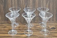Front view of all six etched cocktail glasses arranged in two rows with alternating designs.