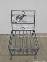 Wrought iron patio chair showing front view with leaf design on backrest and slatted seat base