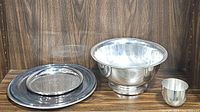 3 etched round metal trays, 1 metal cup, and 1 metal bowl displayed on wooden surface