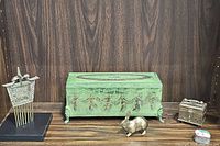 Lot items arranged on wooden surface: green lidded box, vintage metal comb on stand, small metal box, metal rabbit figurine