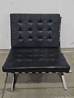 Front view of black leather Barcelona style chair showing tufted seat and back