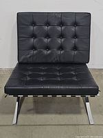 Front view of black leather Barcelona style chair showing tufted seat and back on chrome frame