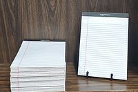 Stack and single display showing the front of the AmazonBasics legal pads, top-bound with black header and ruled white paper