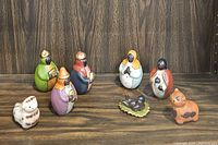 Full view of the entire Nativity Scene set with seven human figures and two small animal figures displayed on wooden surface