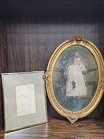 Photo showing both antique oval framed color portrait of a child and smaller rectangular framed sketch of man together.