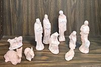 Photo shows the majority of nativity figures including standing Mary, Joseph, Three Wise Men, shepherds, and animals like donkey and sheep, all in stone with pale pinkish-beige paint.