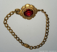 Front view of the gold wash chain bracelet featuring a red oval gemstone in an ornately detailed pendant and matching detailed clasp.