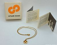 Complete lot showing necklace, original box, and pamphlet.