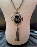 Front view of the black glass butterfly cameo necklace on a display bust showing the pendant, metal ornate frame, and chain tassel.