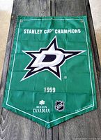 Full front view of the green Dallas Stars 1999 Stanley Cup Champions banner with logos and text visible, banner hanging flat.