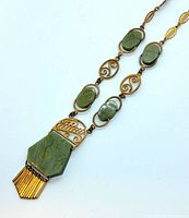 Close-up photo of the vintage statement necklace showing gold-tone links and green jade stones, with detailed pendant and fringe.