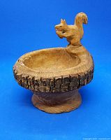 Front side view of the handcarved wooden bowl showing live edge bark detail and squirrel sitting on the rim holding a nut.