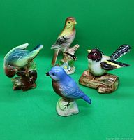 Four vintage Japan porcelain bird figurines together on green background